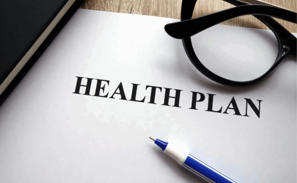 close up of the cover of a health plan with a pair of glasses and ink pen resting on top